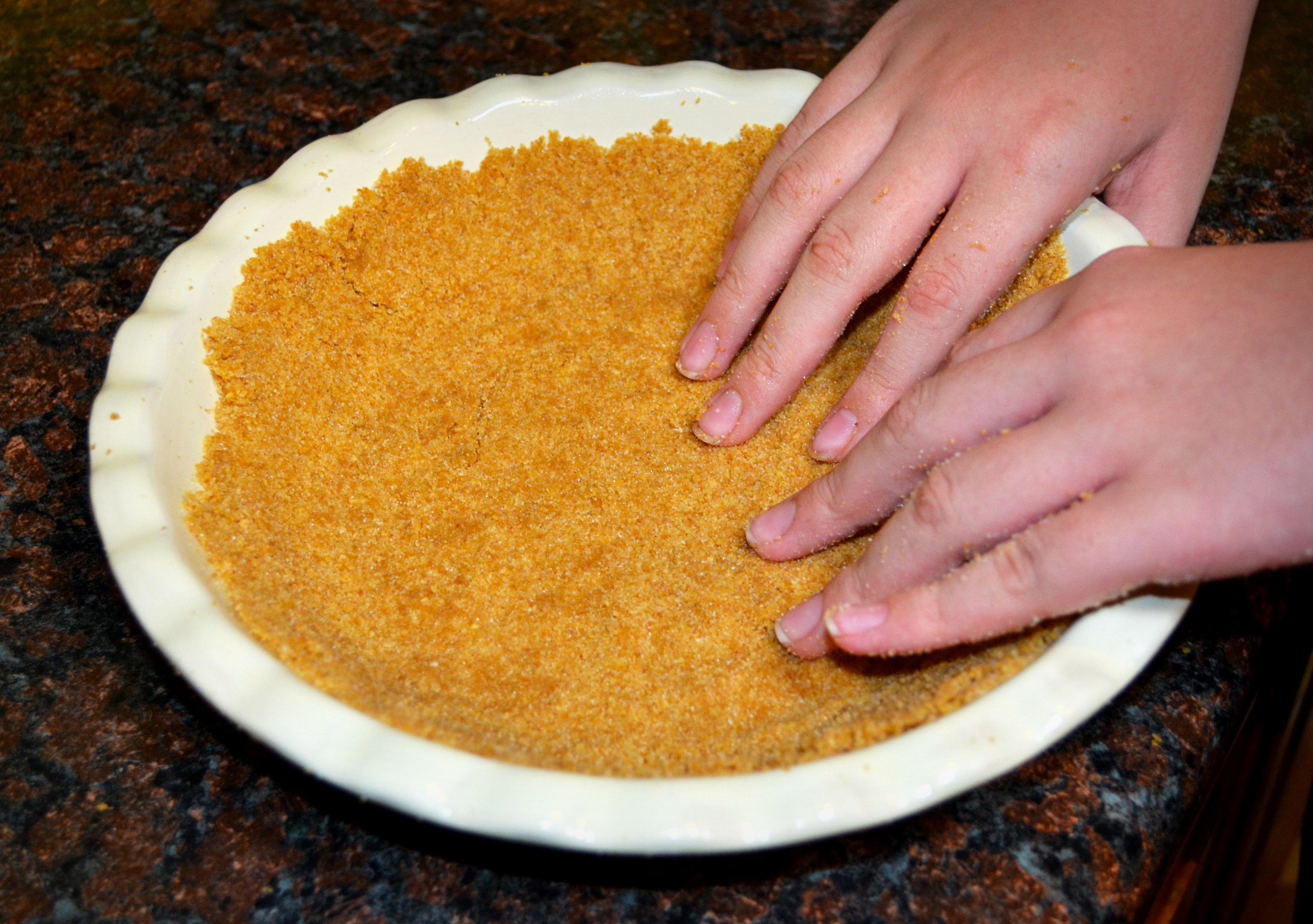 Step six, and this is fun because you get to mess around with the food with your hands - press the crumbs into the pan to form the crust.